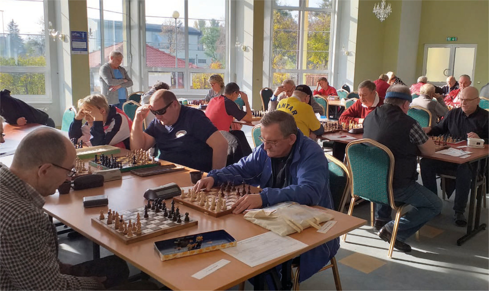 Osoby grające w szachy przy stolikach