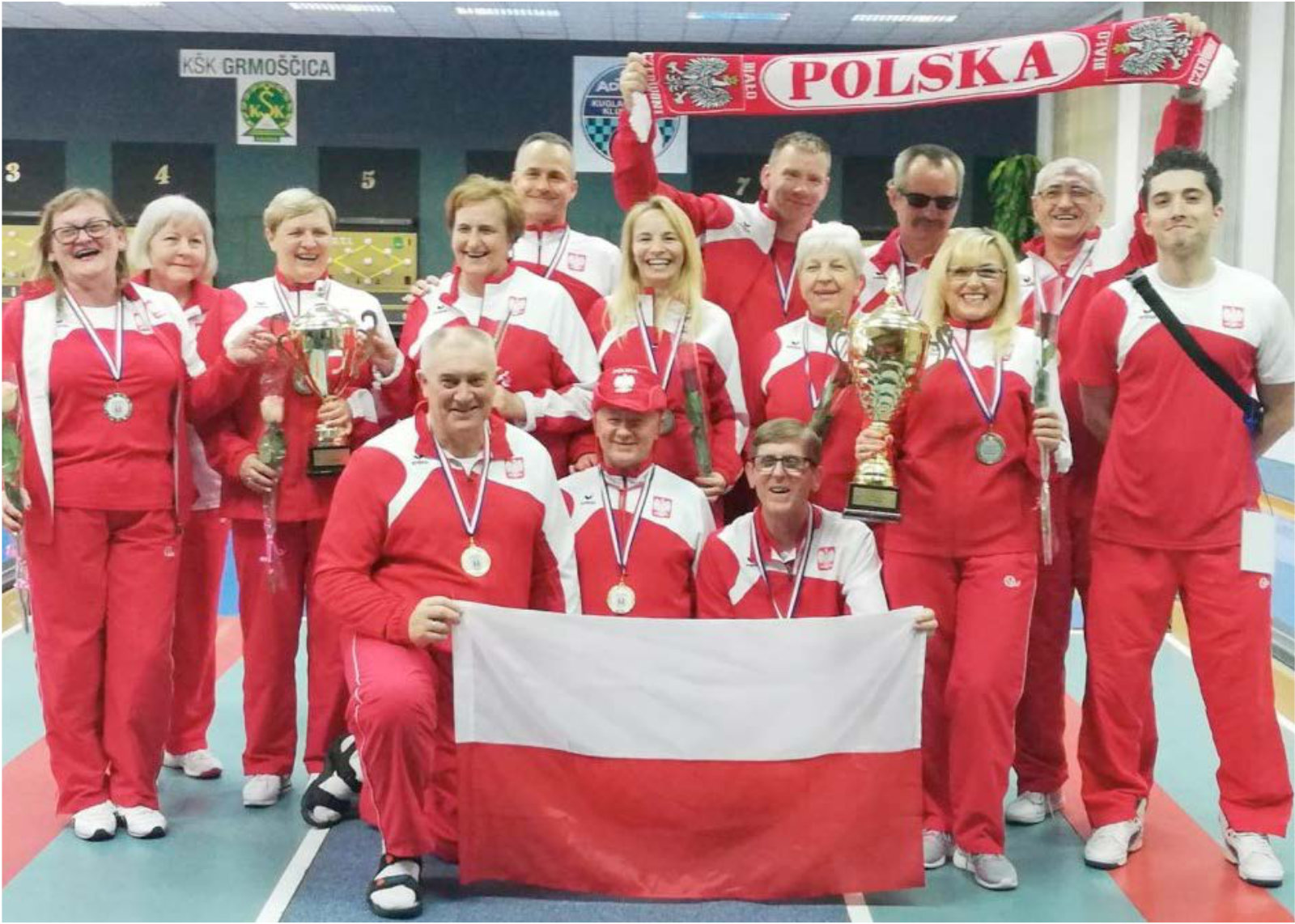 Grupach osób w dresach reprezentacji z flagą i medalami