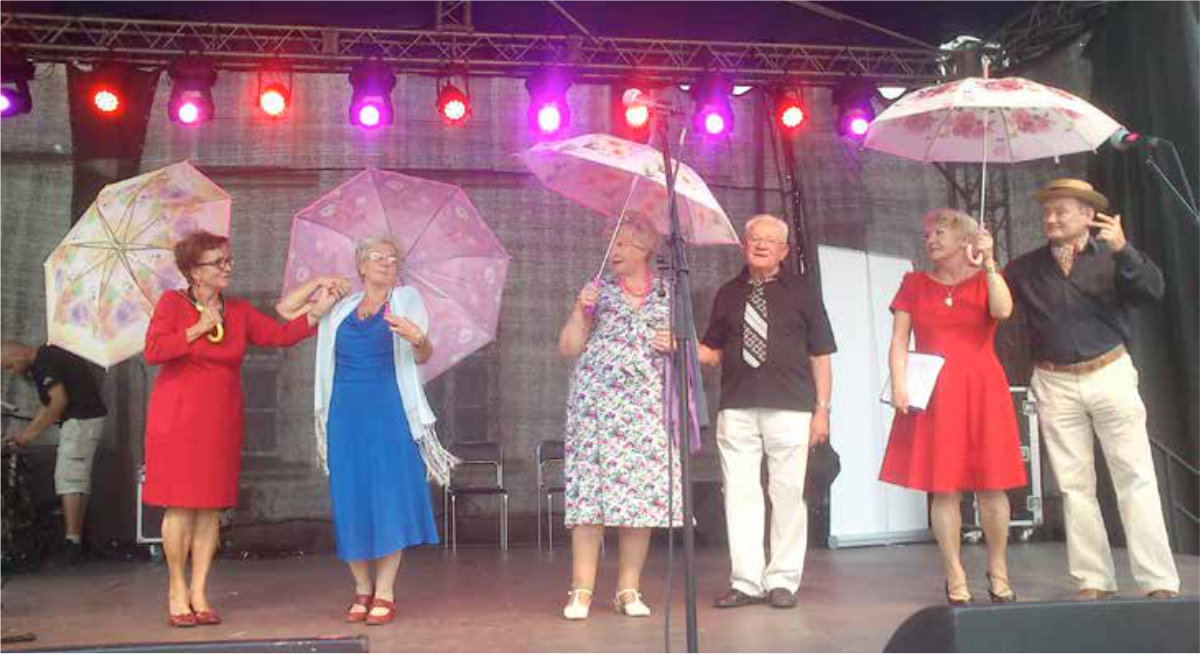 Grupa ludzi z parasolami stojąca na scenie