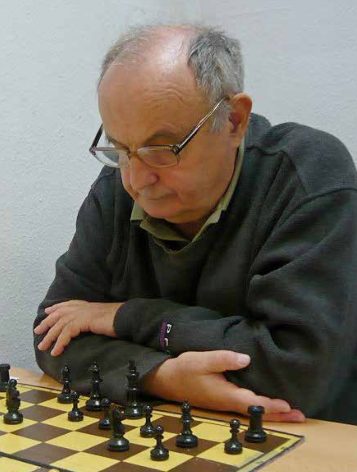 Męzczyzna przygląda się sytuacji na szachownicy przed sobą