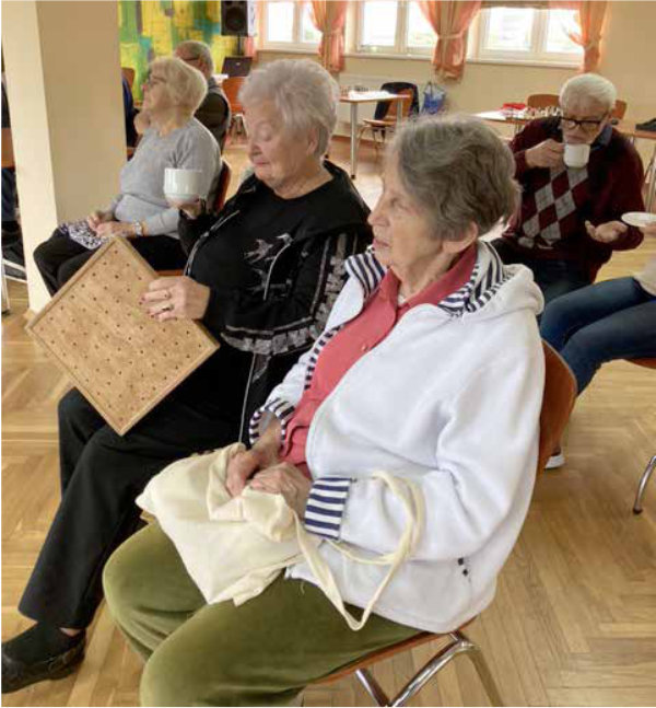 Uczestnicy słuchają wykładu siedząc na krzesłach w sali szkoleniowej.