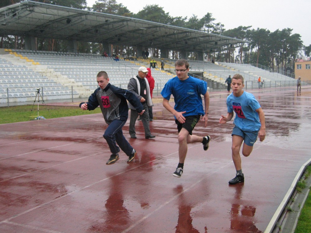 grupa osób w trakcie biegu na stadionie
