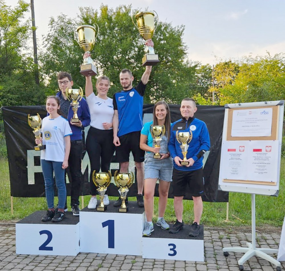 grupa osób na podium z pucharami
