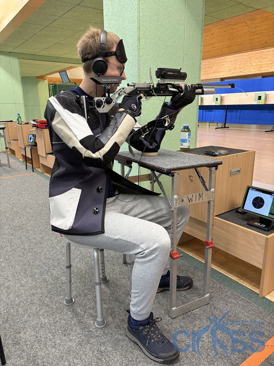 mężczyzna siedzi na strzelciy i trzyma broń