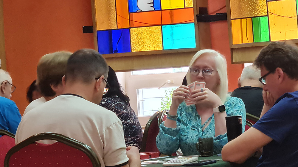grupa osób przy stole z kartami