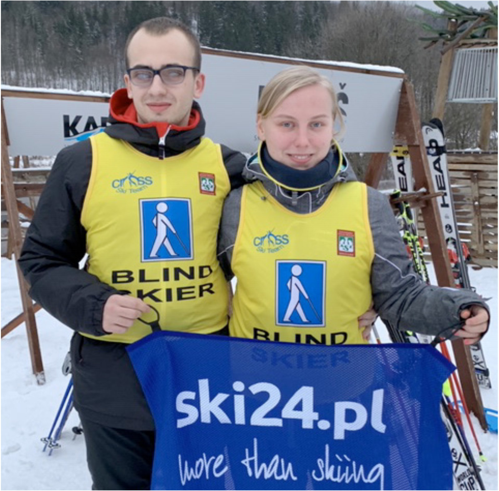 Kobieta i mężczyzna w kamizelkach dla niewidomych trzymający baner reklamowy