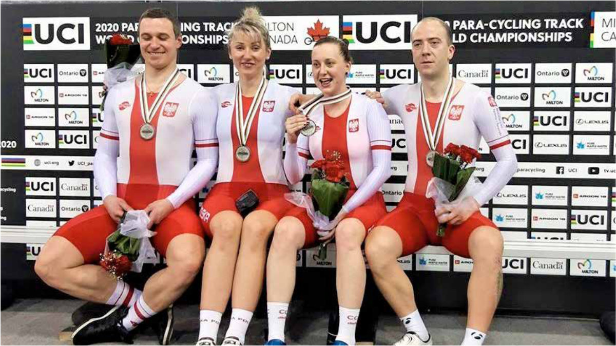 Osoby w strojach reprezentacji z kwiatami i medalami