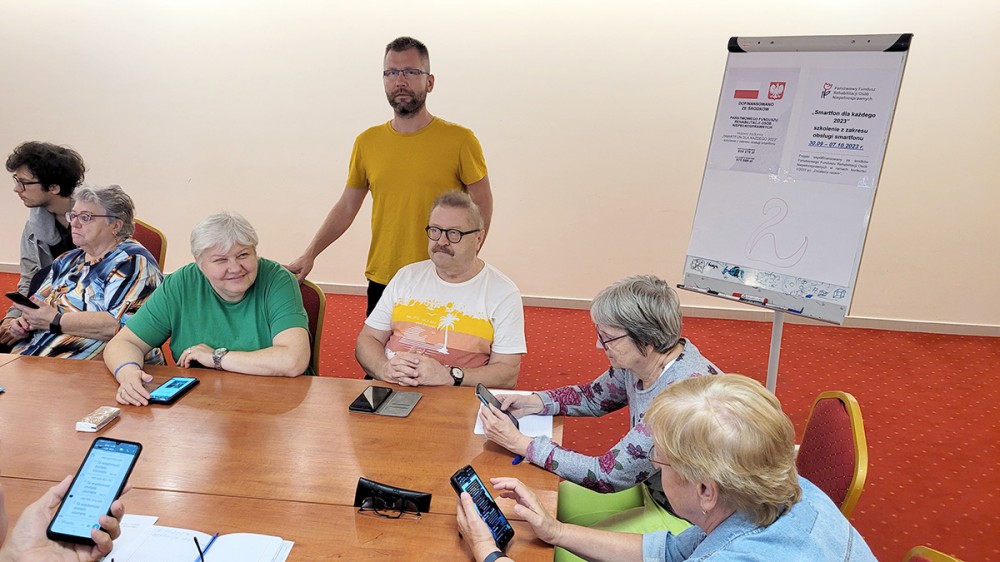 grupa osób z telefonami na sali