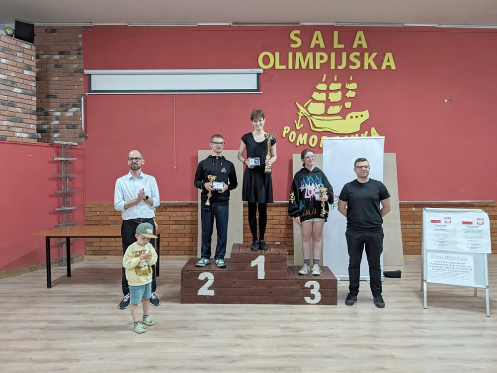 grupa osób na podium z pucharami