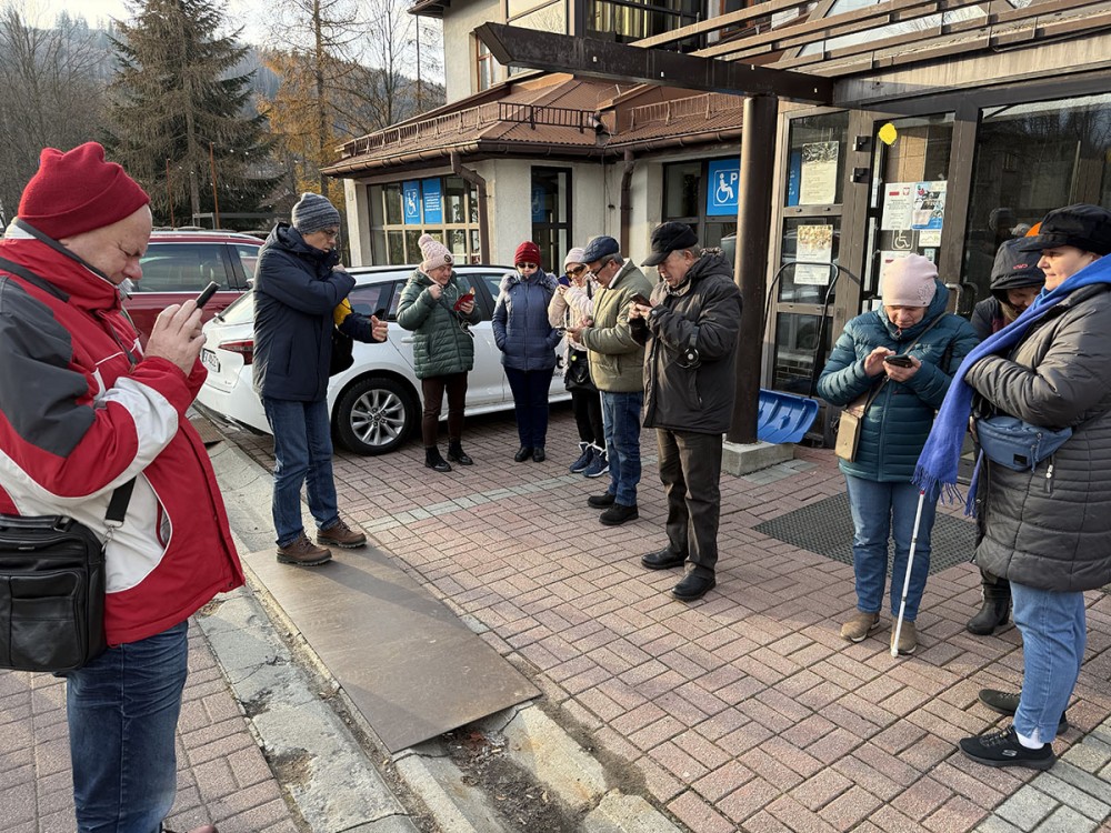 grupa osób przed budynkiem z telefonami w dłoniach