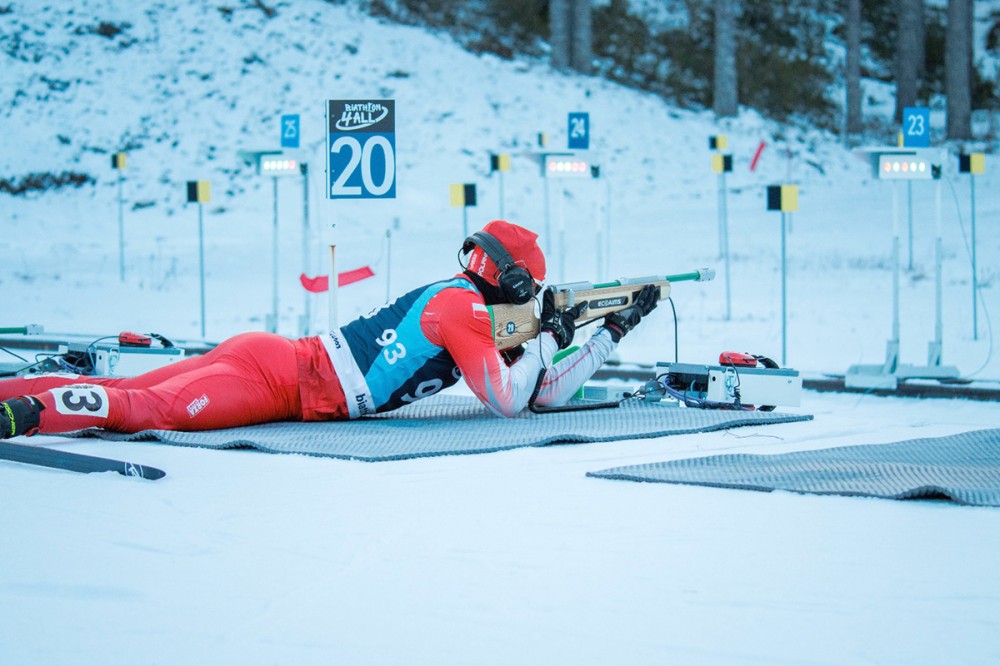 sylwetka osoby leżącej na śniegu z bronią w ręku