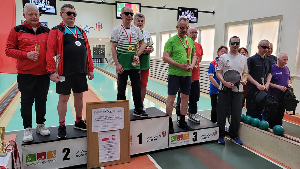 grupa osób z pucharami na podium