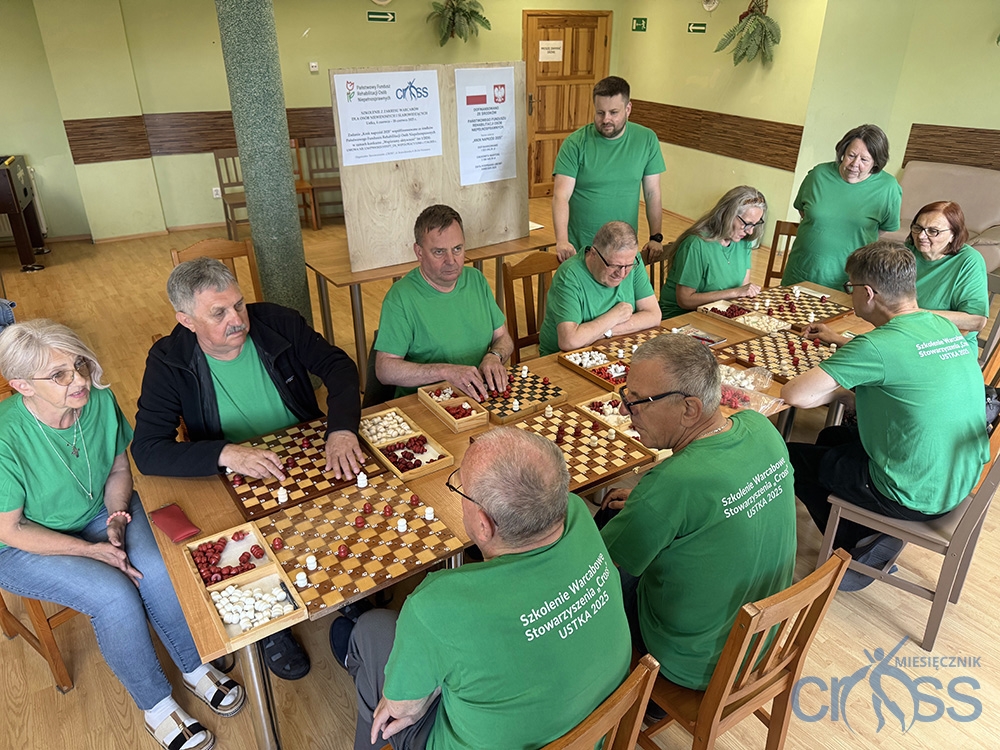 grupa osób przy stolikach z warcabami
